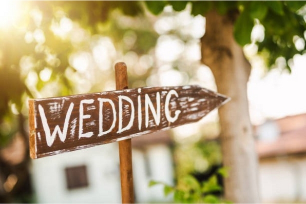 Wooden sign pointing to the right with the word 'Weddings' painted on it.