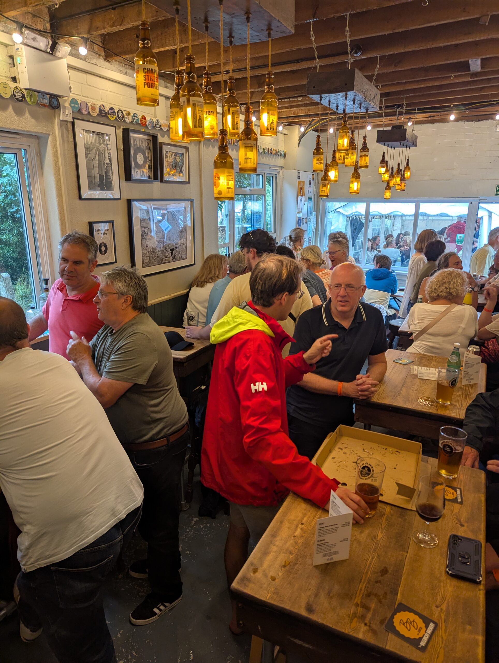 People seated and standing in a micropub taproom drinking beer
